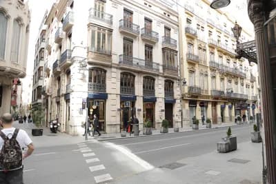Quiet street corner with ornate buildings and pedestrians in Valencia, Spain.