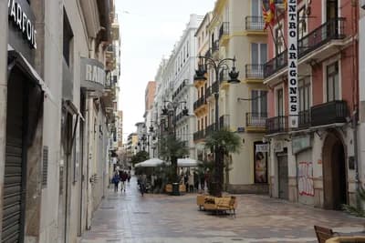 Narrow street with outdoor seating and buildings in Valencia, Spain.