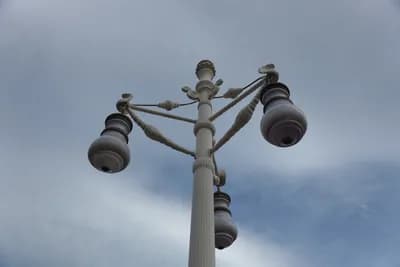 A decorative street lamp with multiple globes against a cloudy sky.