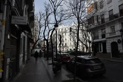A street scene in Valencia with parked vehicles, a scooter, and a 'Zacarias' sign.