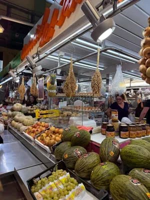 Produits frais à un stand de marché avec des melons et des raisins.