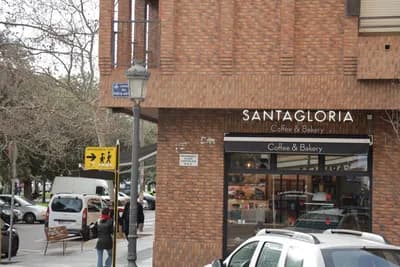Santagloria Coffee & Bakery storefront with pedestrians and parked cars on a street.