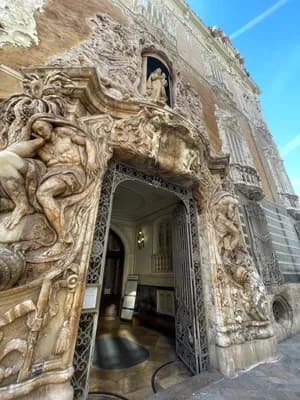 An ornate stone entrance with intricate sculptures and a decorative wrought iron gate.