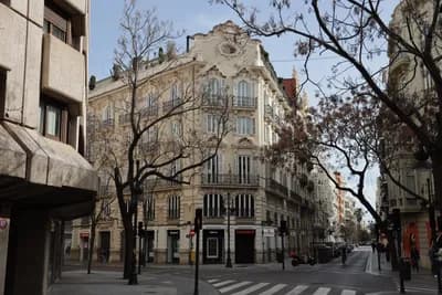 Quiet street corner with ornate buildings and a crosswalk in Valencia, Spain.