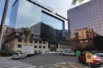 Modern glass buildings reflecting surrounding structures under a clear sky.