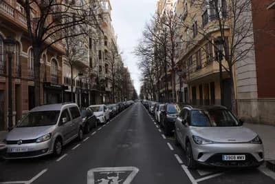 A street scene with parked cars and a bicycle lane in Valencia, Spain.