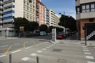 Urban street with parked cars and residential buildings.