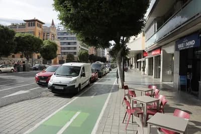 Street view with parked cars, outdoor seating, and a 'BIKE&MIND' sign.
