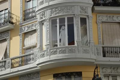 A person cleaning a window in a decorative balcony.