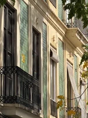 A row of buildings with green-tiled facades and ornate balconies.