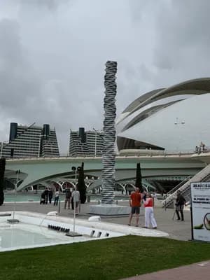 Modern sculpture with people and futuristic architecture in the background.