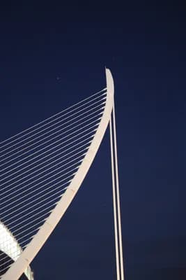 Close-up of a cable-stayed bridge structure against a dark sky.
