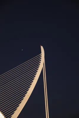 Close-up of a modern cable-stayed bridge structure against a dark night sky with stars.