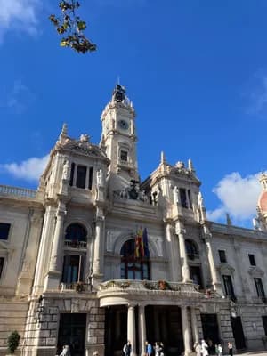 A historic building with intricate architecture and a clock tower, set against a bright blue sky.