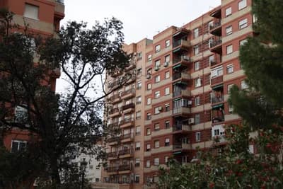 Residential building with balconies and surrounding trees.