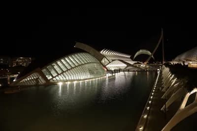 Illuminated modern architecture reflecting on water at night.