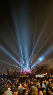 A crowd under blue and white laser lights at night.