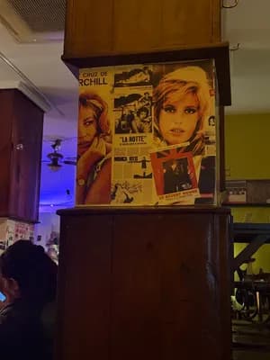 Framed movie poster with woman's face on wooden cabinet in room with ceiling fan and kitchen cabinets.