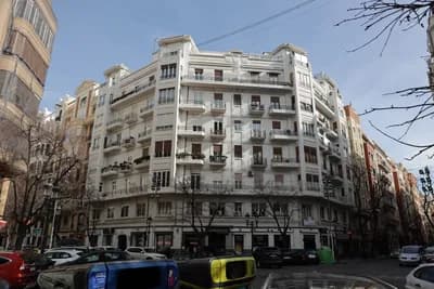 A residential building with balconies and parked cars in front of it.