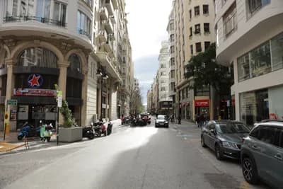 Urban street with parked vehicles and pedestrians.