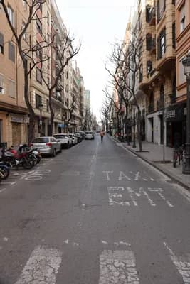 Quiet street with parked motorcycles and cars, pedestrian in the distance.