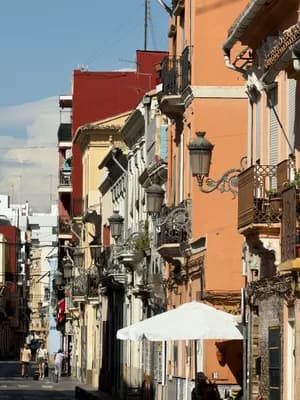 Narrow street with colorful buildings and ornate street lamps under clear blue sky.