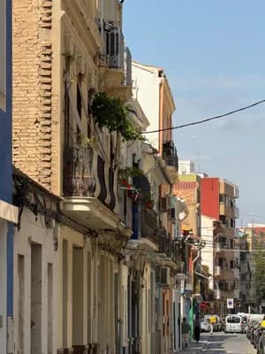 A street scene in Valencia with colorful buildings and parked cars.