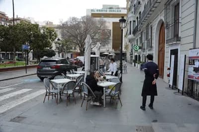 Outdoor café tables with umbrellas on a pedestrian street in Valencia, Spain.