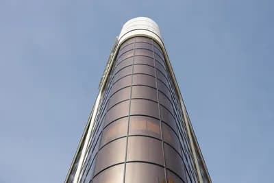 Bâtiment cylindrique moderne avec façade réfléchissante sous ciel dégagé.