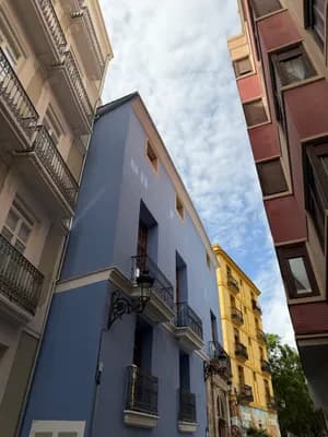 Narrow street with colorful buildings and a partly cloudy sky.