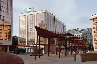 Urban plaza with modern buildings and red pergolas.