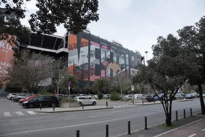 A street view with a colorful mural on a building and parked cars.