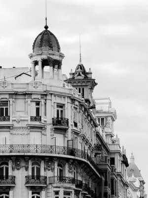 Black and white image of ornate buildings with balconies and decorative architecture.