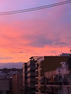 City skyline at sunset with pink and orange skies and silhouetted buildings.