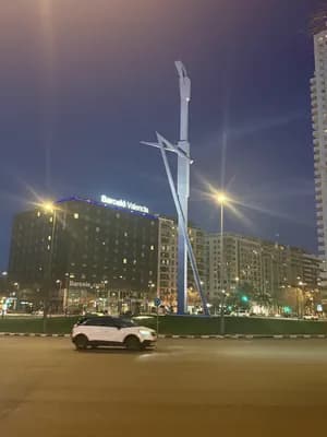 Illuminated modern sculpture in front of the Barceló Valencia hotel at night.