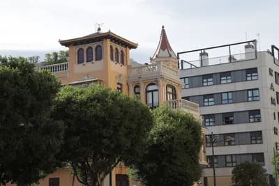 A building with turrets and balconies surrounded by trees.