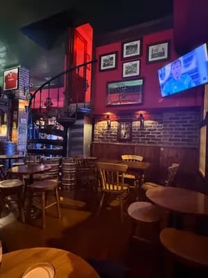 Un bar faiblement éclairé avec des meubles en bois et un escalier.