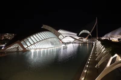 Modern architecture lit up at night with reflections in water.