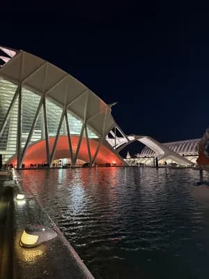 Modern architecture illuminated at night, reflected in water.