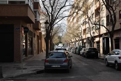 A street scene with parked cars and residential buildings in Valencia, Spain.