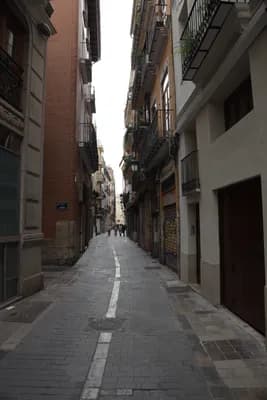 Narrow street with buildings and a pedestrian in the distance.