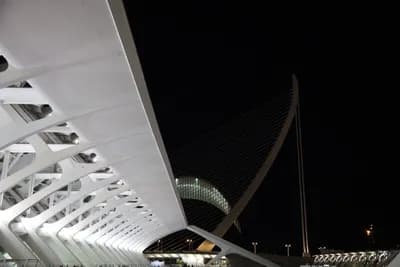 Close-up of modern white metal structure at night with dark sky in background.