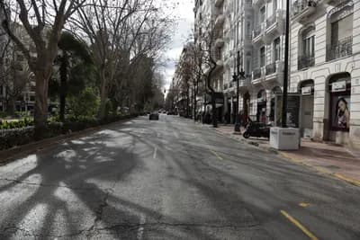Quiet street with palm trees and historic buildings on a sunny day.