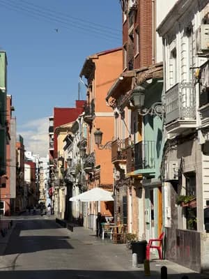 Narrow street with colorful buildings and a white umbrella on the sidewalk.