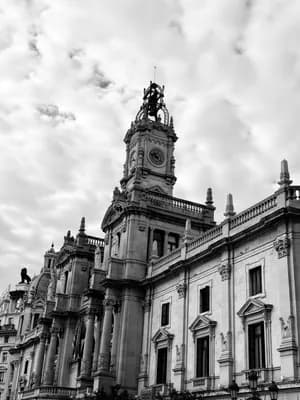 Ornate building with clock tower and statues, black and white.