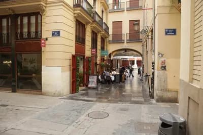 Narrow street with covered walkway and outdoor seating area.