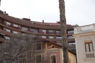Residential buildings with balconies and a palm tree in the foreground.