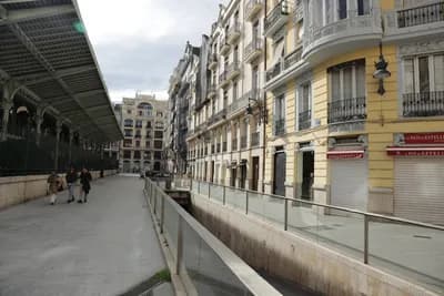 A street with a covered market and buildings, featuring a canal.