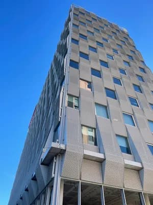 Modern high-rise building with textured facade and clear blue sky.