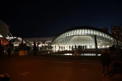 Modern glass structure at night with people around